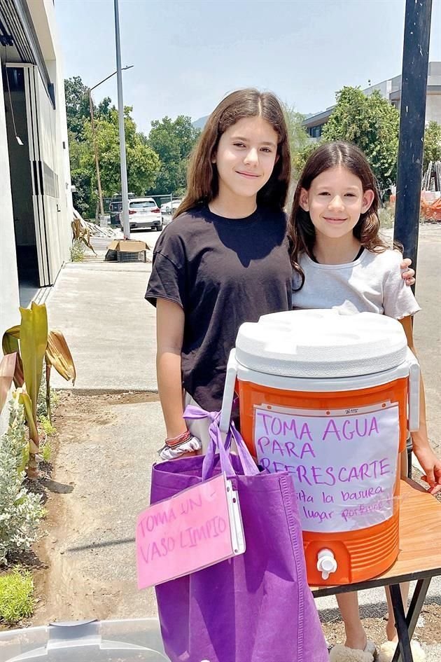 Dos niñas residentes de la Colonia Jerónimo Siller, en San Pedro instalan un termo con agua para regalar a los transeúntes de la zona.