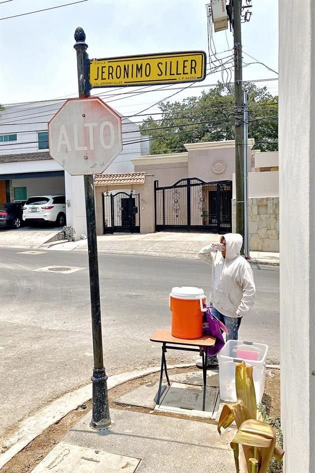 Dos niñas residentes de la Colonia Jerónimo Siller, en San Pedro instalan un termo con agua para regalar a los transeúntes de la zona.