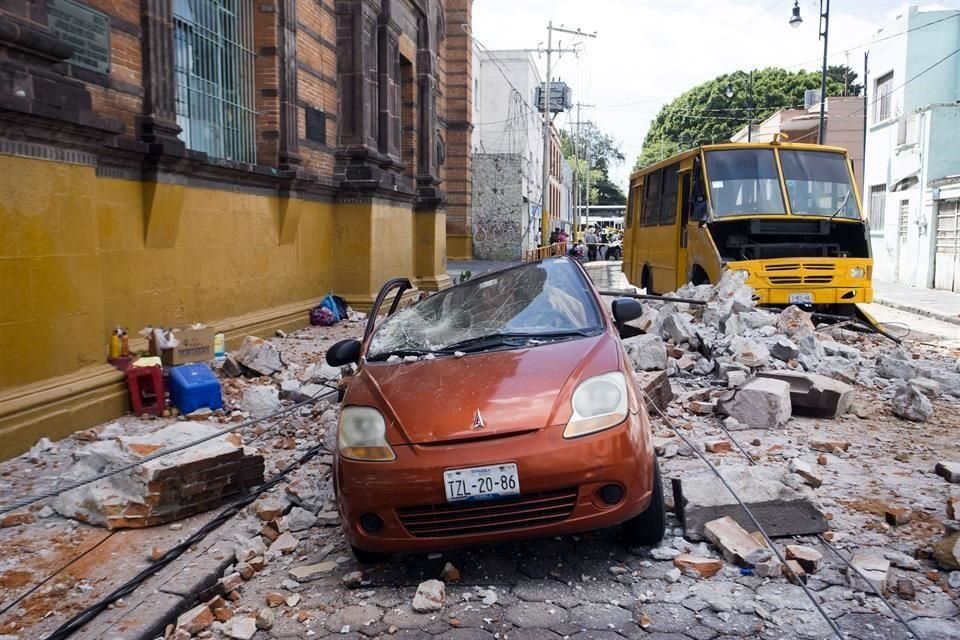 Un automóvil quedó destrozado por los trozos de concreto que se desprendieron de un edificio, en el Centro de Puebla.