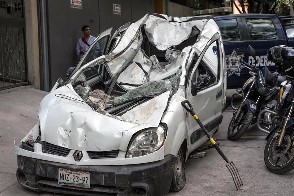 Un hombre camina cerca de un automóvil destruido después del sismo.