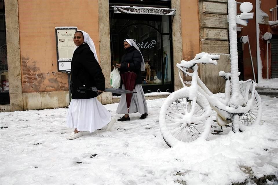 Dos monjas caminan sobre la nieve en el centro de la capital italiana.