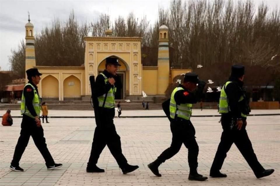 Oficiales de China caminan frente a una mezquita en Kashgar, Xinjiang.