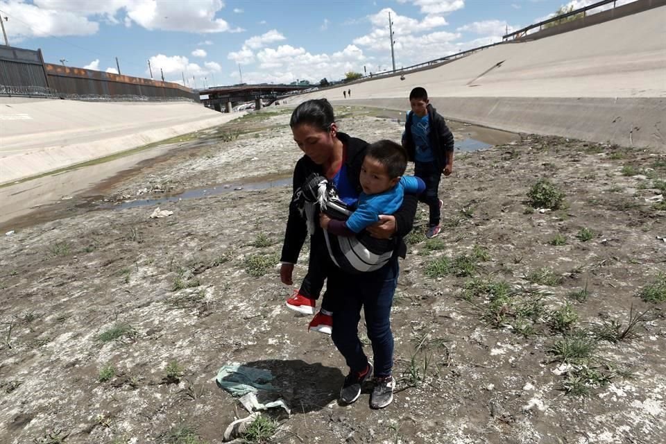 Migrantes caminan frente al muro fronterizo entre México y Estados Unidos, cerca del Puente Internacional Santa Fe, en Ciudad Juárez, estado de Chihuahua, México, el 11 de mayo de 2019.