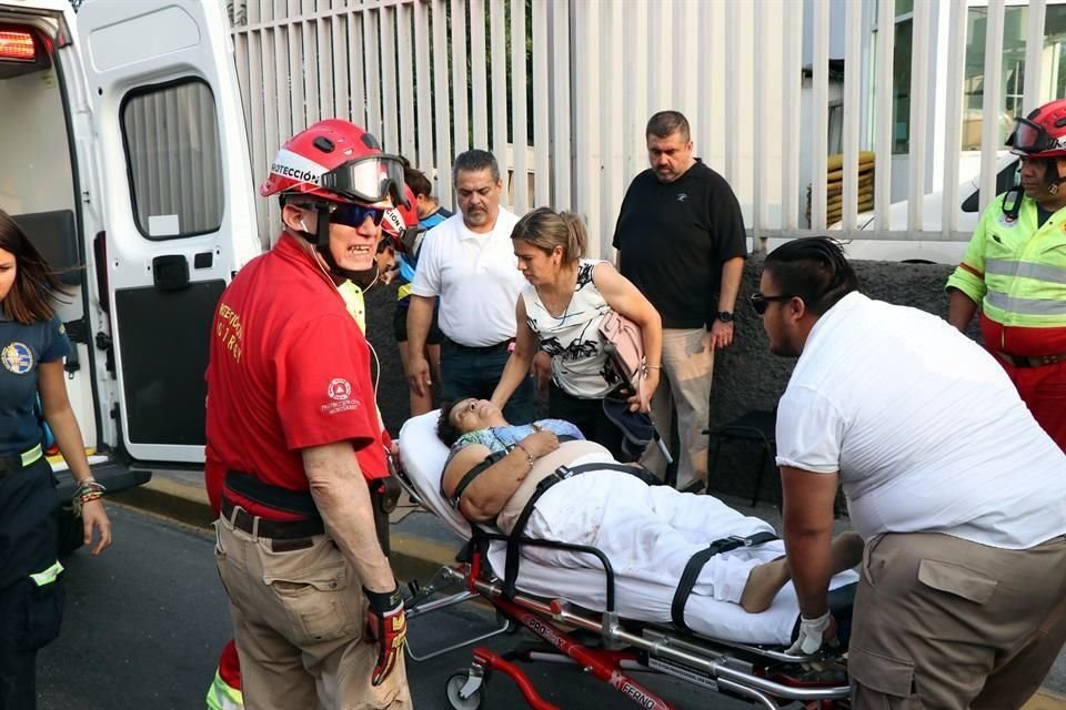 Socorristas auxilian a una pasajera para trasladarla a una ambulancia y llevarla a un hospital.