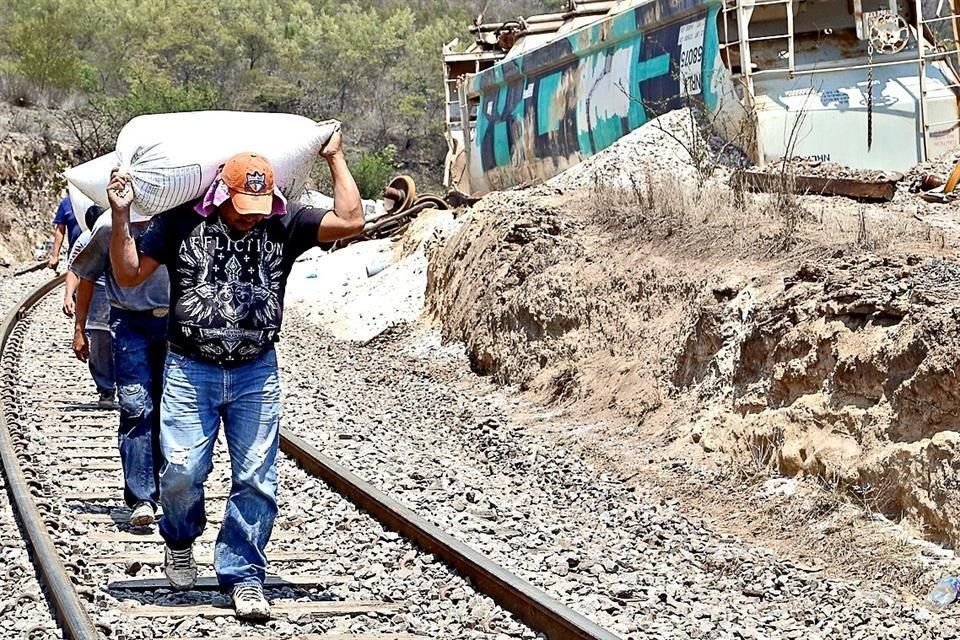 En Acultzingo, Veracruz, trabajadores retiran costales de polietileno que no pudo robar el crimen tras descarrilar el tren.