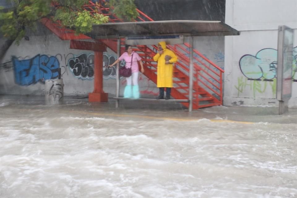 Usuarios del transporte urbano tuvieron que subirse a la parada del camión para evitar ser alcanzados por las inundaciones en el Bulevar Díaz Ordaz.