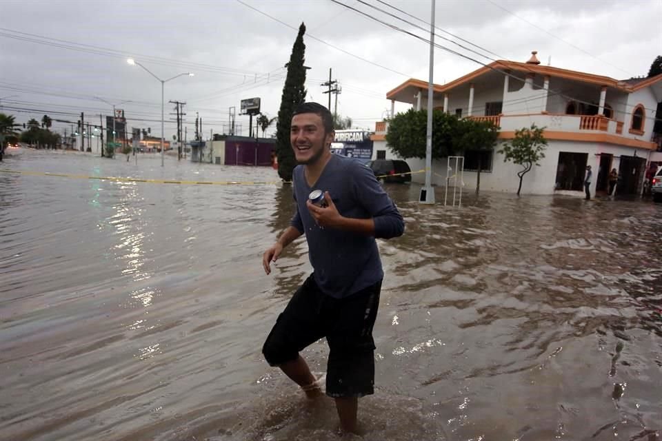 Un vecino en Las Puentes salva su cerveza y sale de su hogar que está inundado.