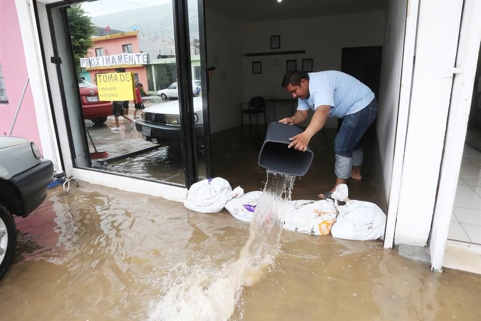 Un vecino de la Colonia Valle de Santa Lucía saca el agua de su casa con un bote de basura.