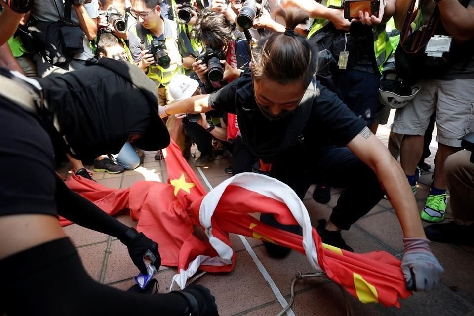Un manifestante rompe la bandera China a la que después prendieron fuego.