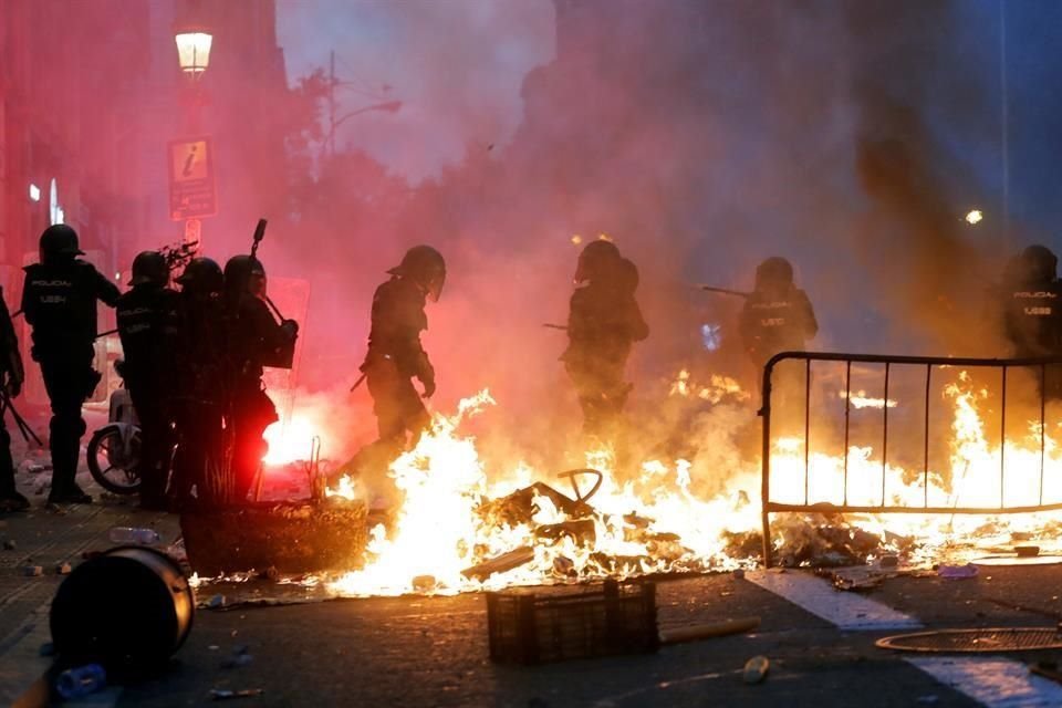 Policías junto a una barricada incendiada, durante las protestas en Barcelona.