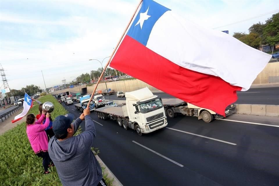 Ciudadanos muestran su apoyo a una manifestación de camiones y vehículos este viernes, en el marco de las protestas antigubernamentales que cuplen una semana, en Santiago, Chile.