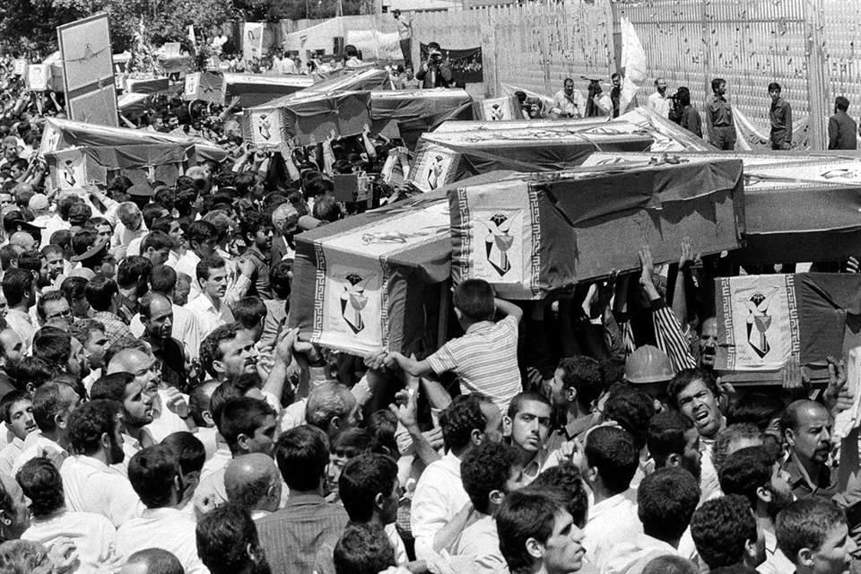 Iraníes cargan los ataúdes de algunas víctimas durante el funeral masivo en 1988.