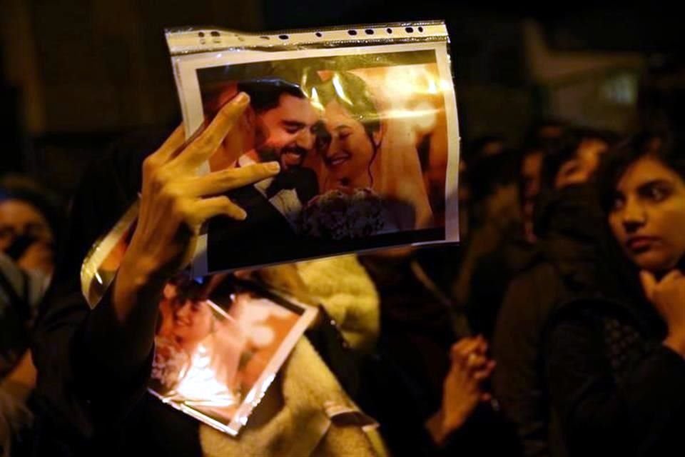 Una manifestante muestra el sábado fotografías de dos personas que murieron en el avión derribado accidentalmente por Irán.