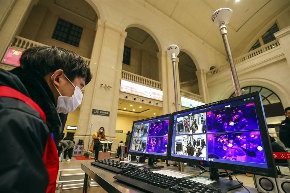 Un trabajador monitorea la temperatura de los pasajeros en la estación de Hankou, en Wuhan.