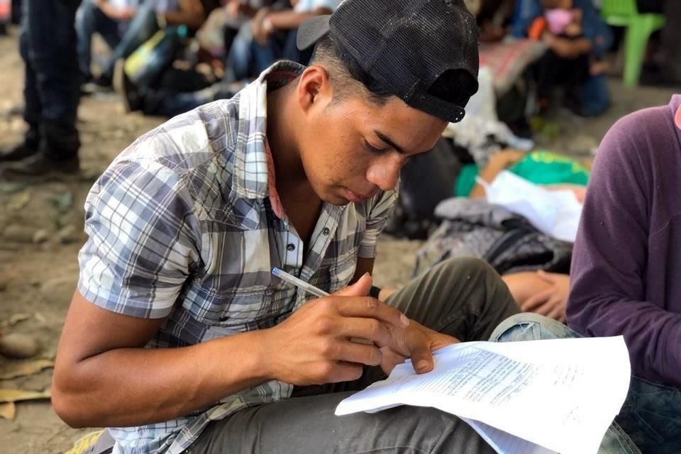 Un migrante llena un formato de solicitud.