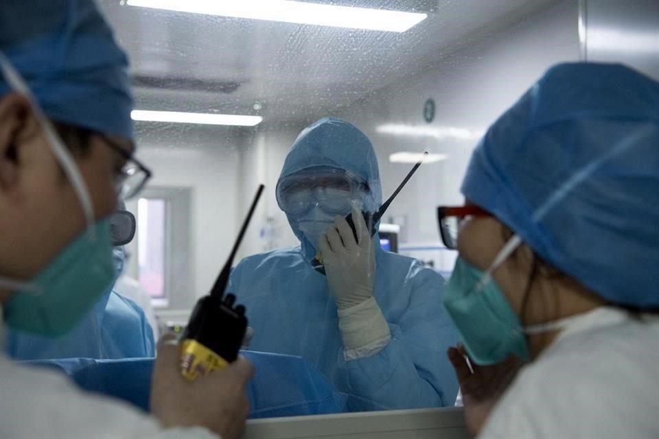 Imagen del 31 de enero de 2020 de doctores, separados por la ventana de una sala de aislamiento, hablando sobre opciones de tratamiento con intercomunicadores en el Hospital de Neumología de Fuzhou.