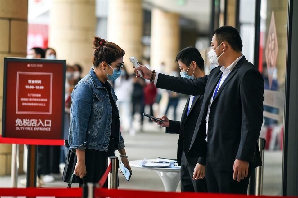 Un trabajador toma la temperatura corporal de una clienta en una tienda libre de impuestos en Haikou, en la provincia de Hainan, en el sur de China.