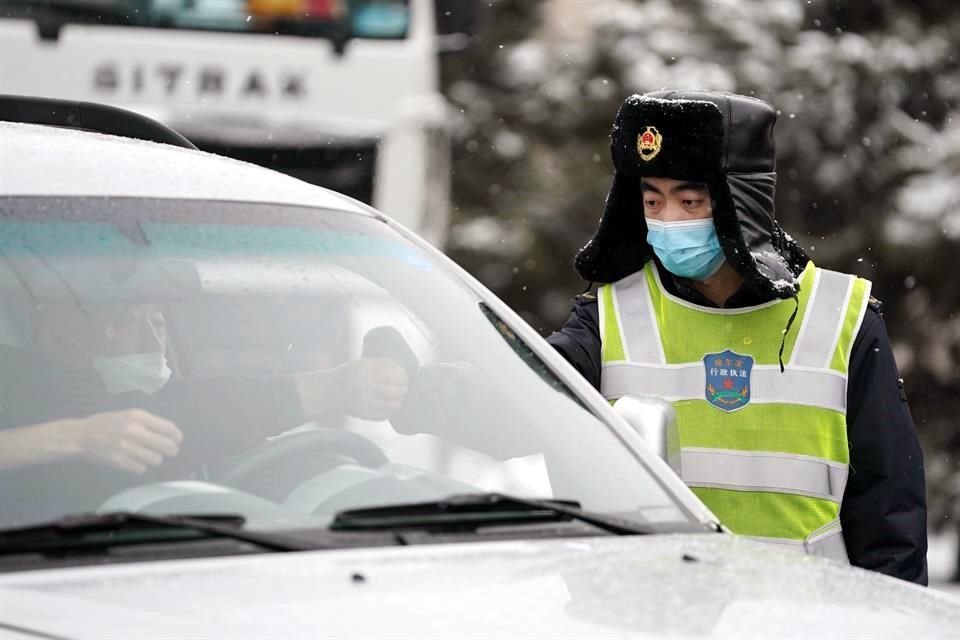 Un trabajador verifica la temperatura corporal de un conductor en la nieve, en un punto de verificación para la prevención de la epidemia en la ciudad de Harbin.