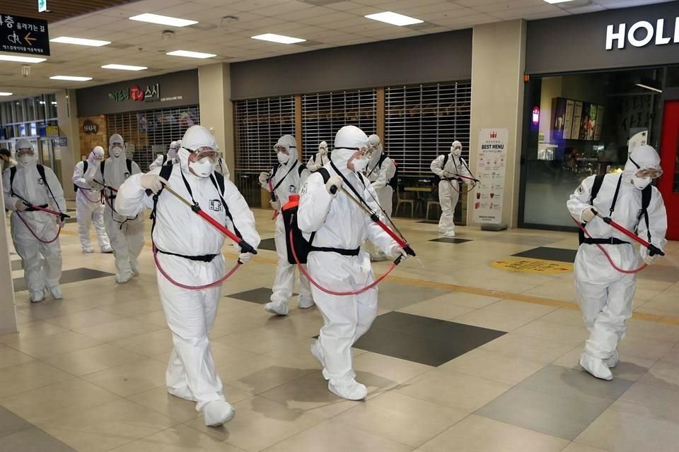 Soldados surcoreanos con equipo de protección desinfectan la estación de tren de Daegu.