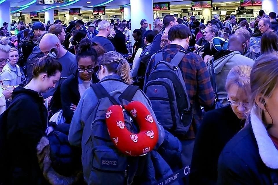 Viajeros provenientes de Madrid esperan en el aeropuerto internacional de Chicago.