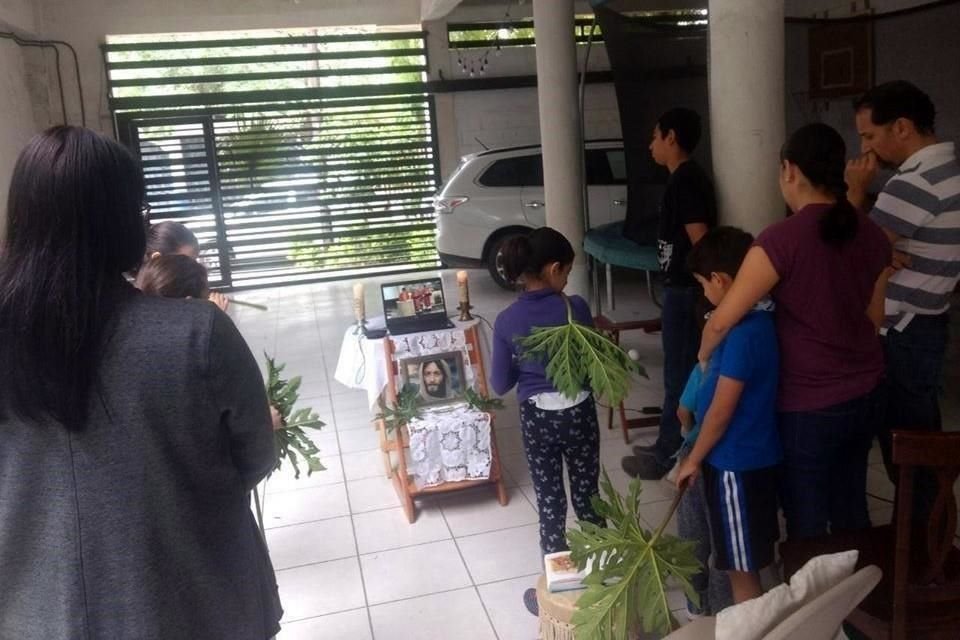 En la cochera de su casa, con una laptop y hojas a manera de palmas, esta familia siguió la misa por redes sociales. 