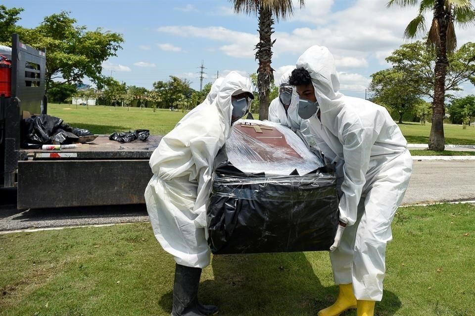 Trabajadores del cementerio Parque de la Paz cargan un ataúd con un fallecido por Covid-19 en Guayas.