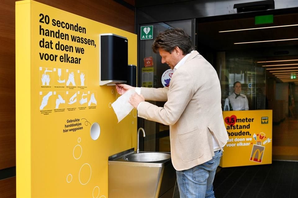 A customer cleans his hands before entering a prototype location of fast food giant McDonald's for restaurants which respect the 1.5m social distancing measure, amid the coronavirus disease.