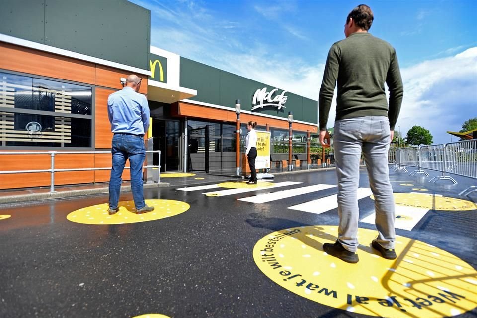 Customers wait outside on social distancing markings at a prototype location of fast food giant McDonald's for restaurants which respect the 1.5m social distancing measure.