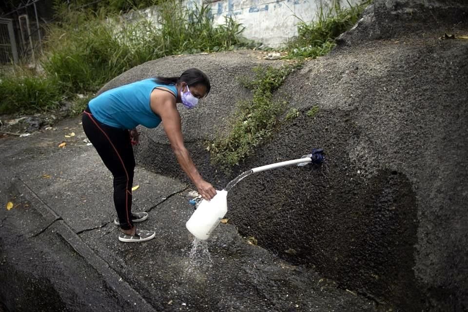 Una mujer recoge agua junto a un camino en Caracas, Venezuela.