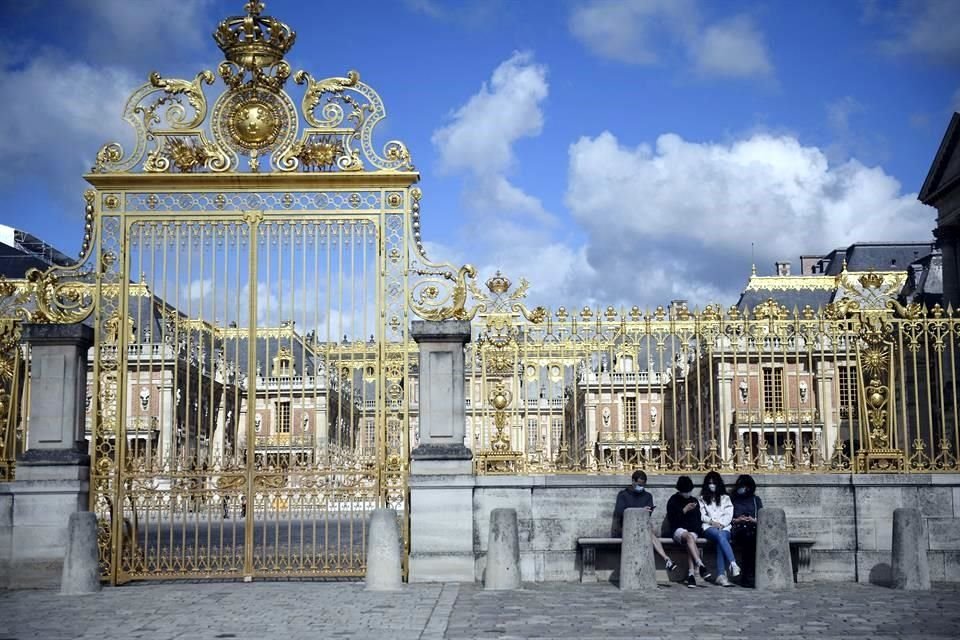 Visitantes sentados a las puertas del Palacio de Versalles durante su reapertura.