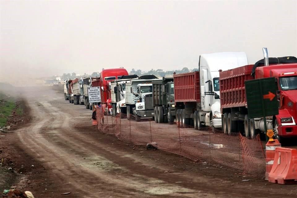 Decenas de unidades cargadas de tezontle esperan su ingreso a la zona donde se construyen las obras complementarias del Nuevo Aeropuerto 'General Felipe Ángeles' tras el retiro de un plantón.