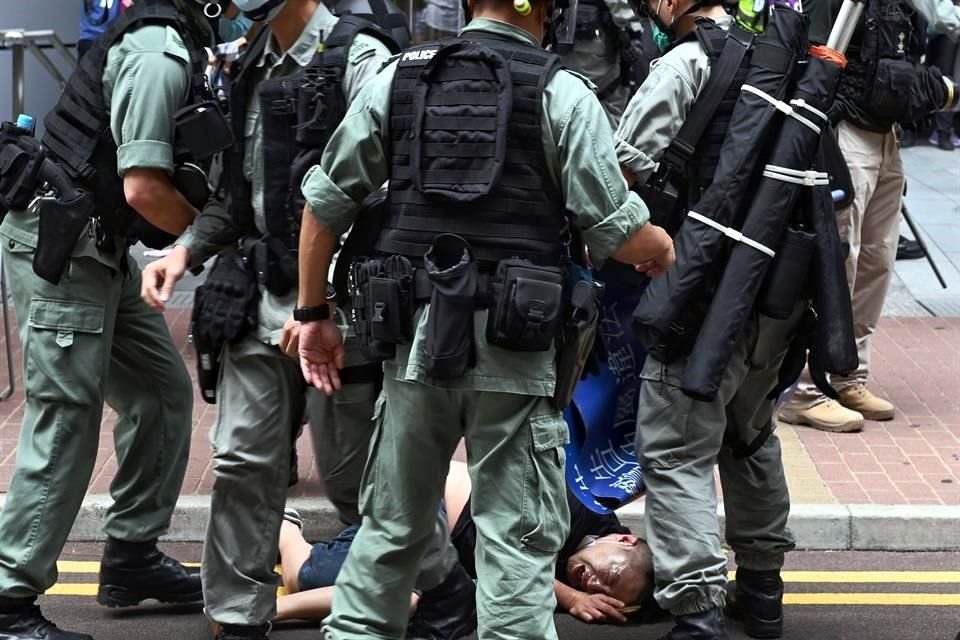 Varios policías detienen a un manifestante tras rociarle la cara con gas pimienta durante una protesta contra la nueva ley de seguridad nacional en Hong Kong.