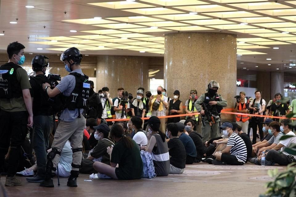 Detenidos durante una manifestación permanecen sentados bajo custodia policial.