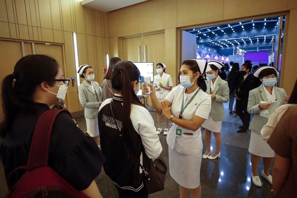 Enfermeras toman la temperatura a un grupo de mujeres antes de entrar a una feria de empleo en Bangkok.