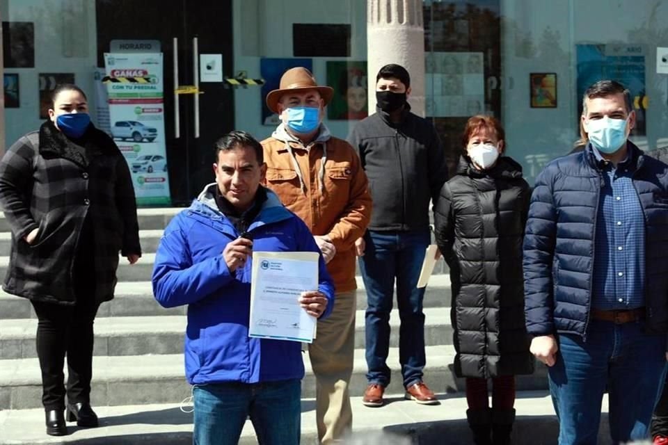 Alfonso Robledo recibe la constancia de Mauro Guerra, dirigente estatal en la Plaza Principal, frente a la antigua Presidencia Municipal.