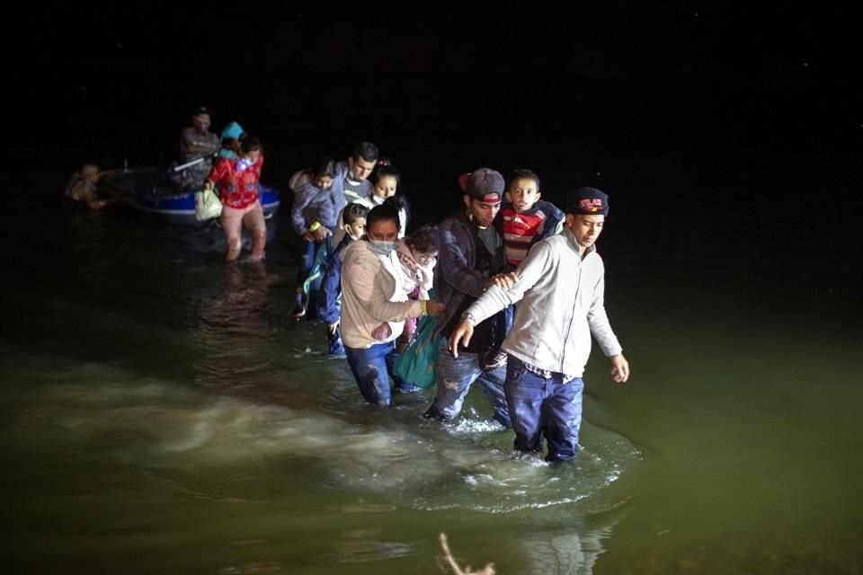 Familias migrantes, la mayoría de Centroamérica, caminan hacia la orilla estadounidense del Río Bravo.