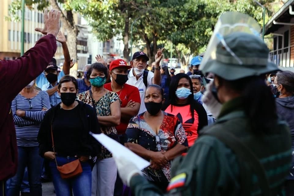 Personas en un barrio de Caracas discuten con funcionarios sobre una casilla que no abrió a tiempo.