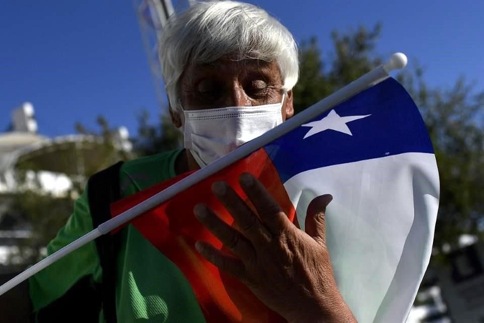 Un votante chileno abraza y besa la bandera de su país al votar este domingo.