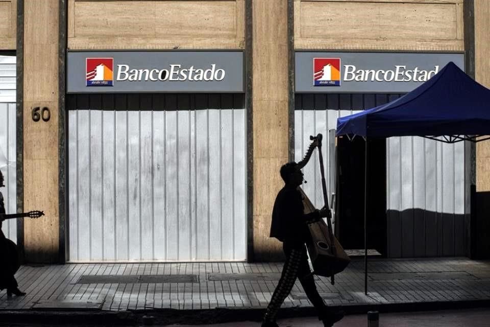 Un músico camina este lunes frente a una sucursal de Banco Estado, en Santiago.