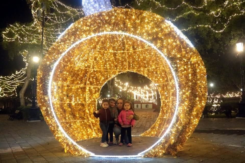 Paseantes disfrutan de las instalaciones iluminadas por luces de colores.