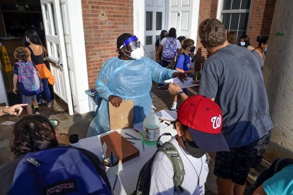 Una trabajadora de salud da instrucciones a padres y alumnos que llegan a la escuela Oyster-Adams Adams, en Washington, en agosto pasado.