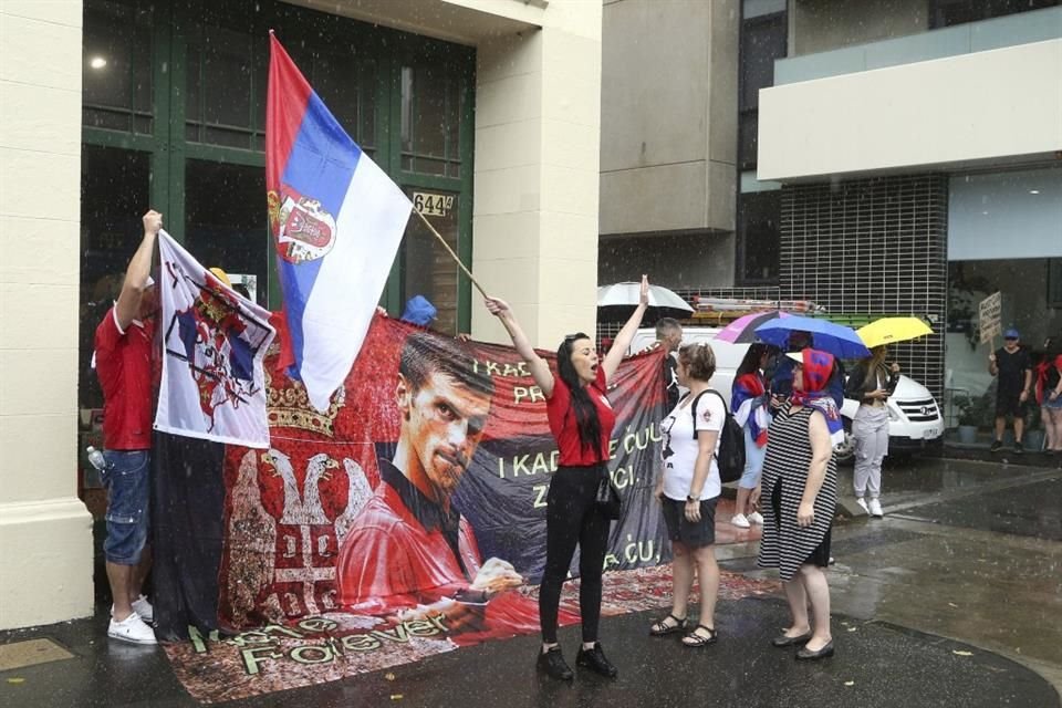 Con pancartas, banderas y gritos, un grupo de personas apoya a Djokovic.