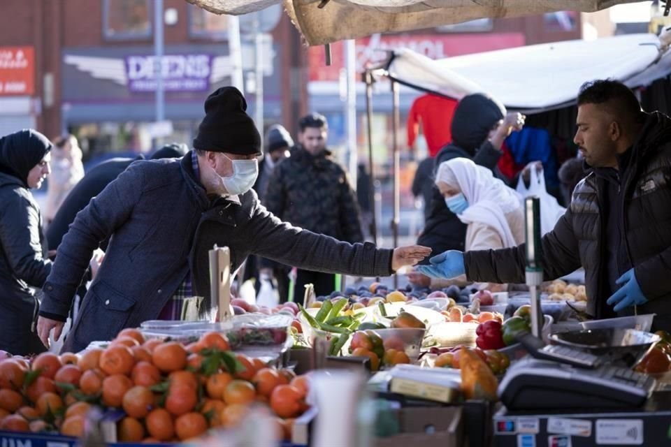 Británicos realizan compras en un mercado de Manchester.