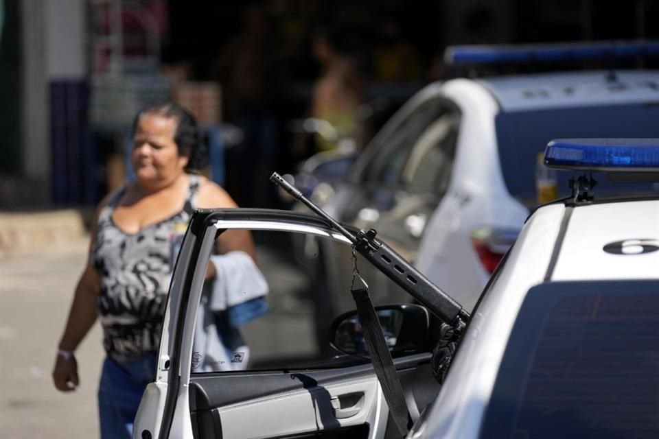 Un policía baja de su patrulla con un arma larga en las favelas de Río.