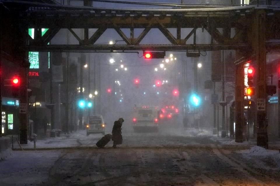 Un peatón en Chicago batalla con el viento y la nieve mientras camina por la calle.