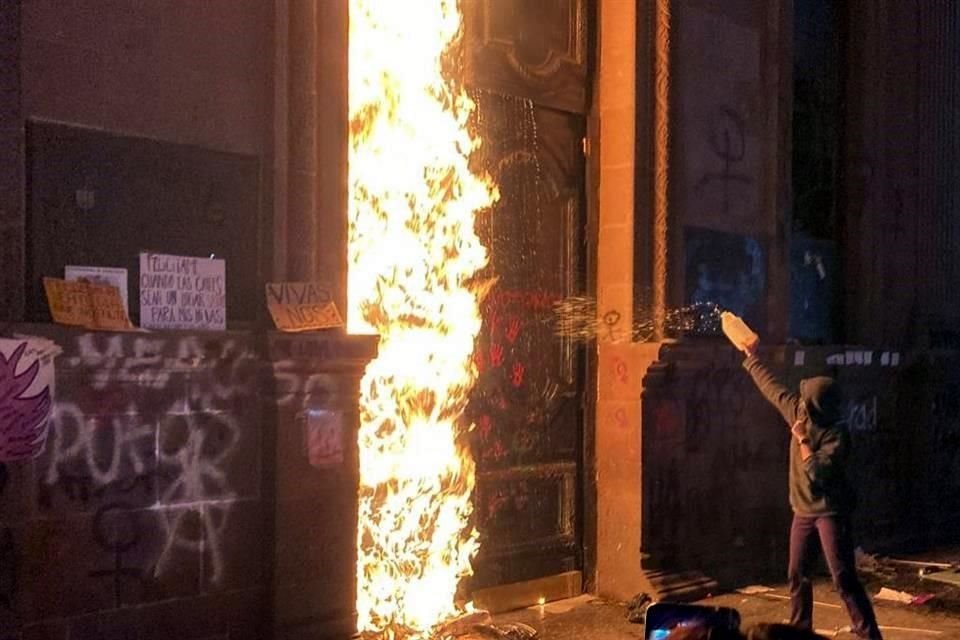 Una manifestante lanza combustible a una columna de fuego en la puerta del Palacio de Gobierno.