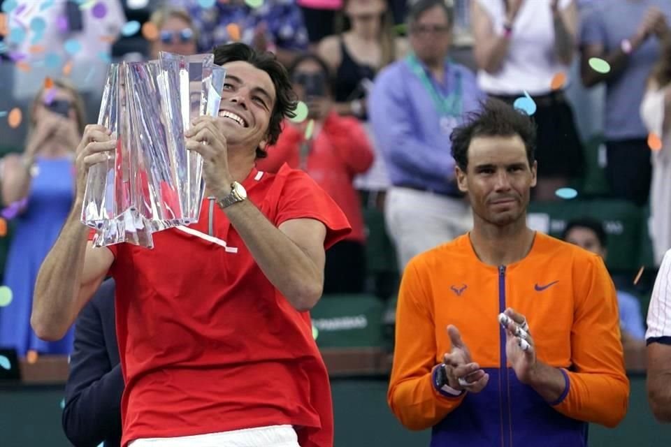Taylor Fritz levanta el trofeo de campeón ante los aplausos de Rafael Nadal.