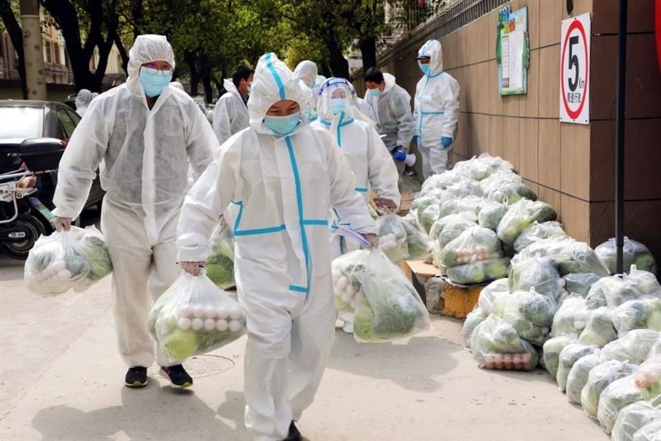 Voluntarios llevan productos básicos para residentes, en el distrito de Fengxian, en Shanghái.