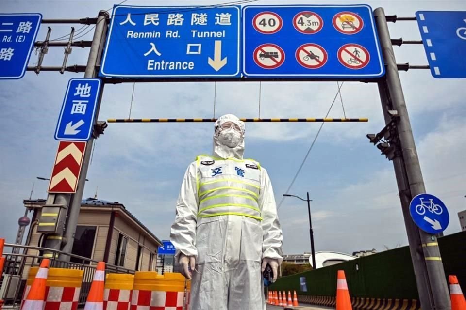 Un oficial de tránsito, con traje protector, controla el acceso a un túnel en dirección al distrito Pudong, que está en confinamiento.