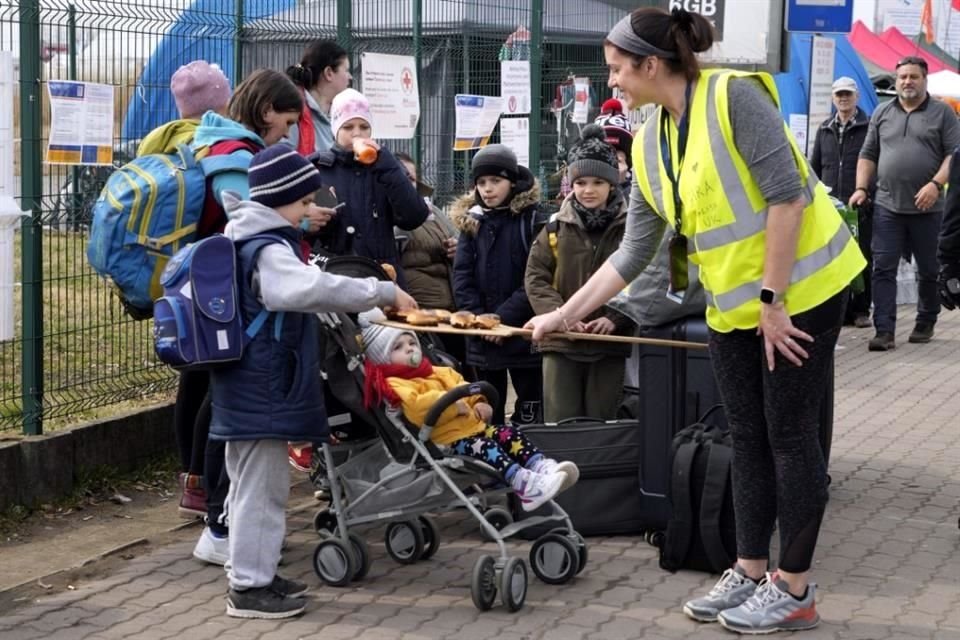 Una voluntaria ofrece donas a los refugiados de Ucrania que han llegado al punto fronterizo con Polonia, en Medyka.